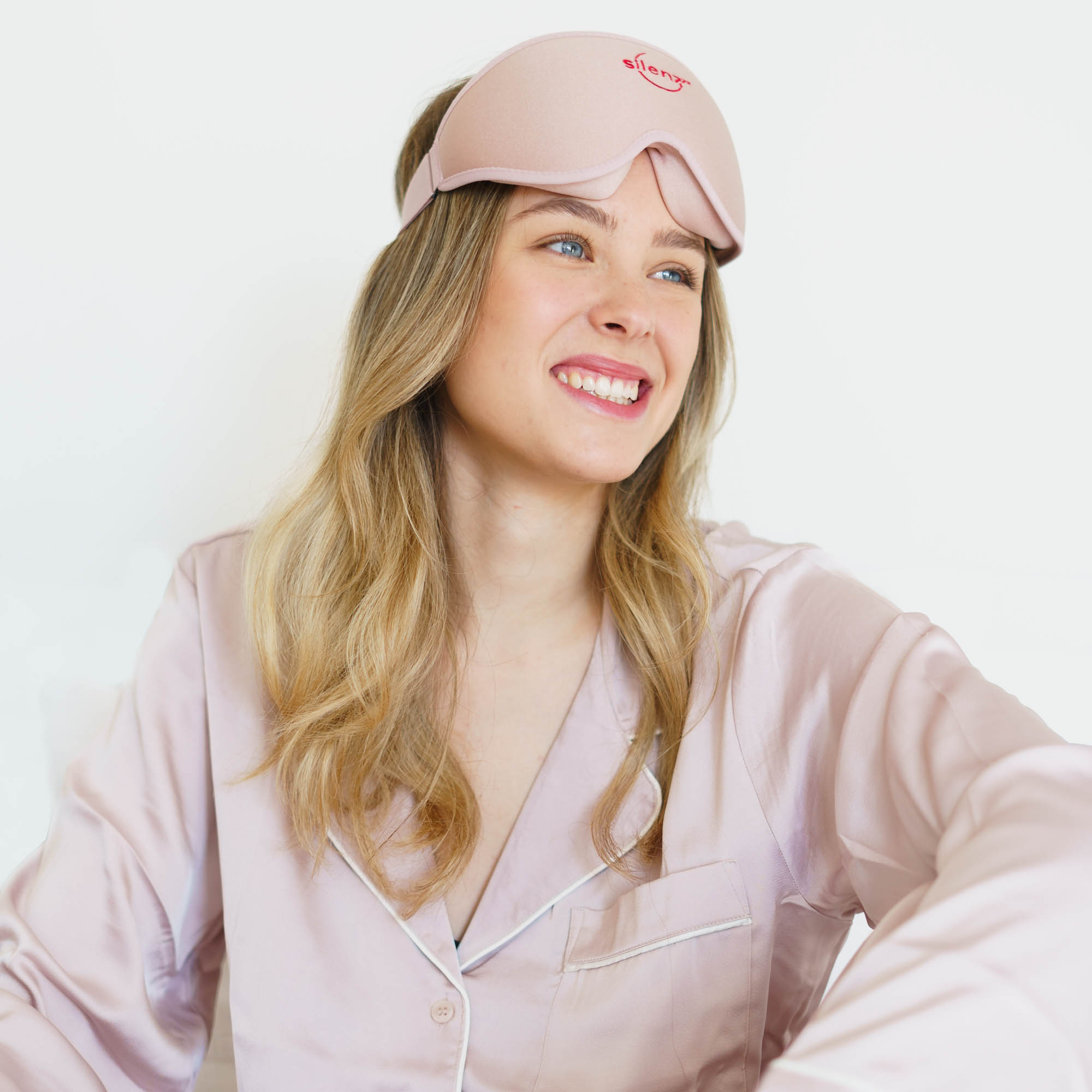 Model grinst mit rosa Schlafmaske